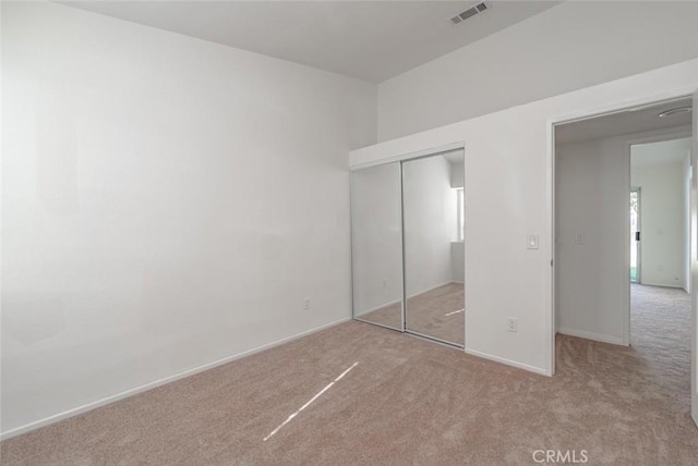 unfurnished bedroom featuring light colored carpet and a closet