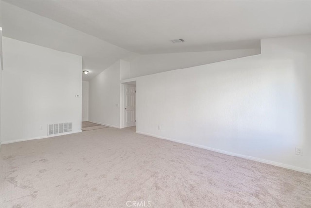 carpeted spare room with vaulted ceiling