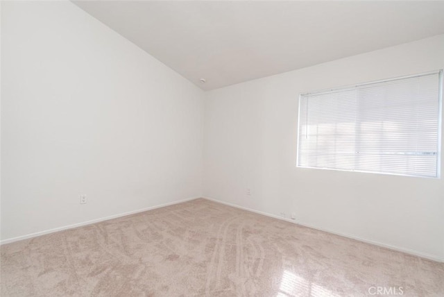 carpeted empty room featuring vaulted ceiling