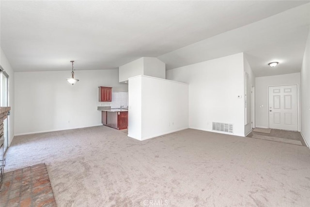 unfurnished living room with sink, light colored carpet, and lofted ceiling