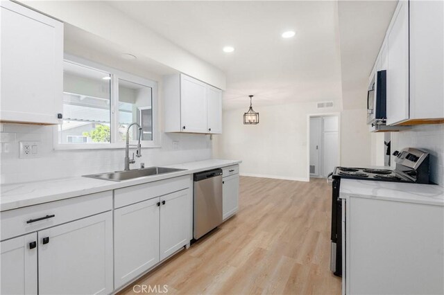 kitchen with decorative light fixtures, stainless steel appliances, light hardwood / wood-style floors, white cabinets, and sink