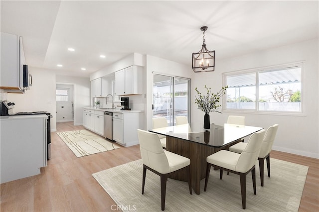 dining room with a notable chandelier, light hardwood / wood-style flooring, and sink