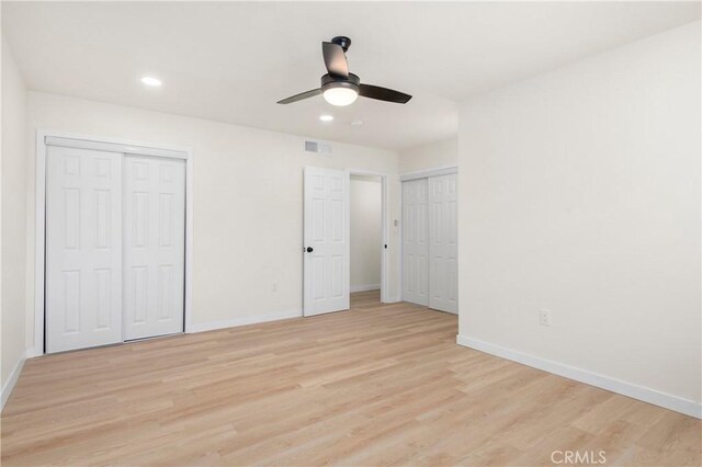 unfurnished bedroom featuring two closets, ceiling fan, and light hardwood / wood-style floors