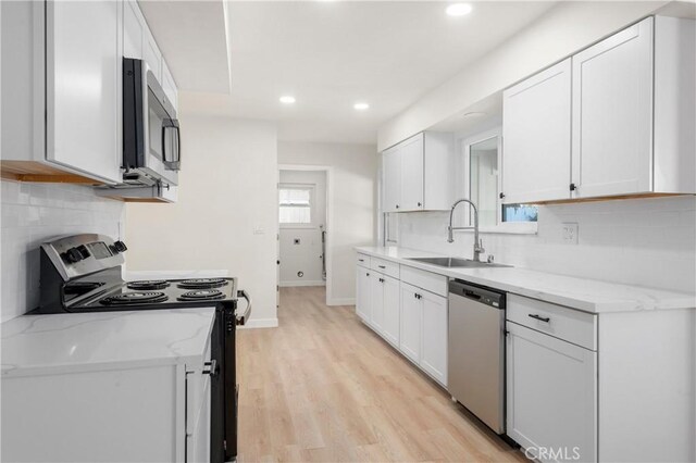 kitchen with sink, white cabinets, light stone counters, and appliances with stainless steel finishes