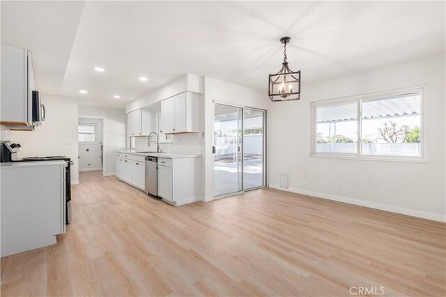 kitchen featuring white cabinets, dishwasher, stove, light hardwood / wood-style flooring, and a chandelier