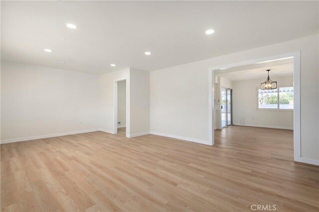 unfurnished room featuring light hardwood / wood-style floors and a chandelier