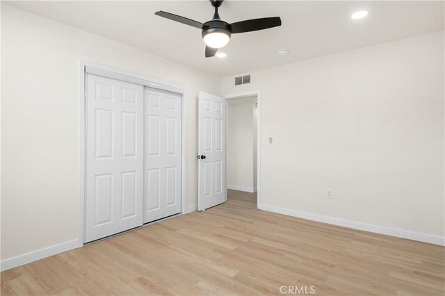 unfurnished bedroom featuring light wood-type flooring, ceiling fan, and a closet