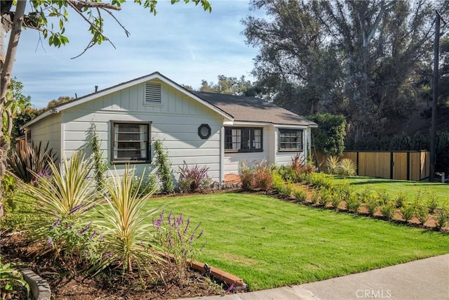 single story home featuring fence, a front lawn, and board and batten siding