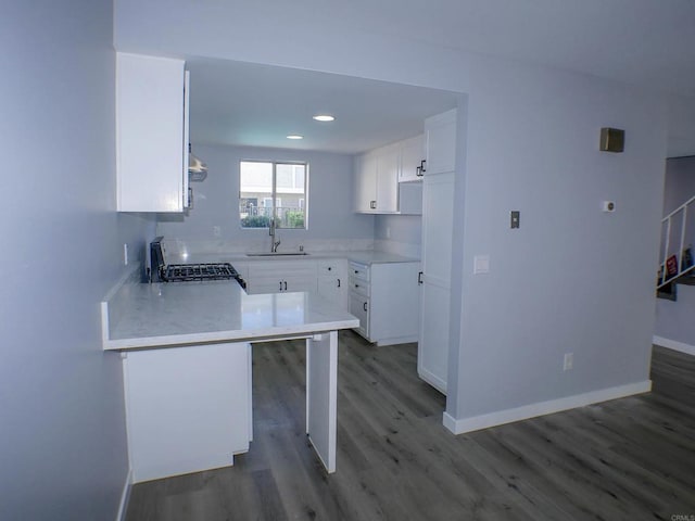 kitchen with sink, white cabinets, stove, and kitchen peninsula