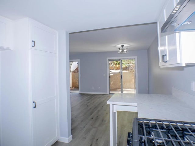 kitchen featuring extractor fan, white cabinetry, hardwood / wood-style flooring, and light stone counters