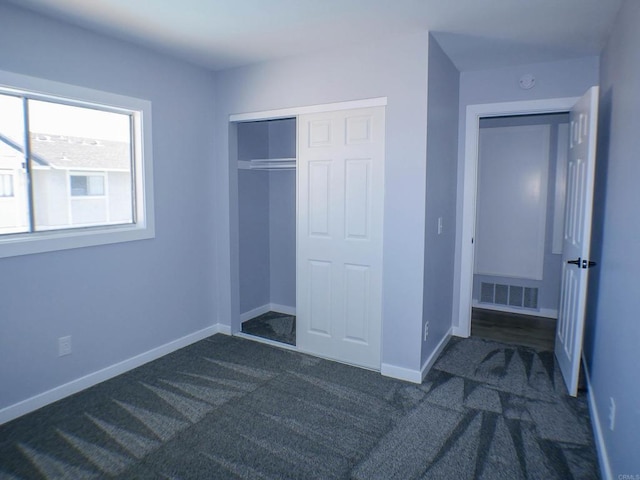 unfurnished bedroom with a closet and dark colored carpet