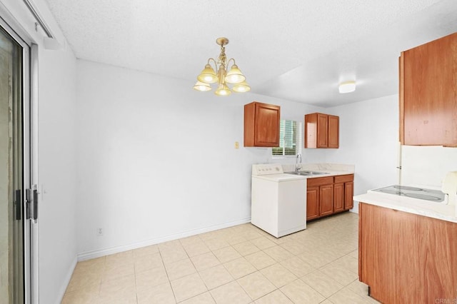 kitchen with decorative light fixtures, washer / dryer, an inviting chandelier, stove, and sink