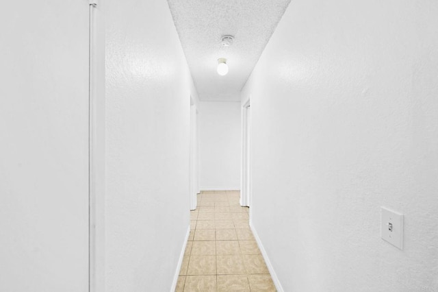 corridor featuring a textured ceiling and light tile patterned flooring