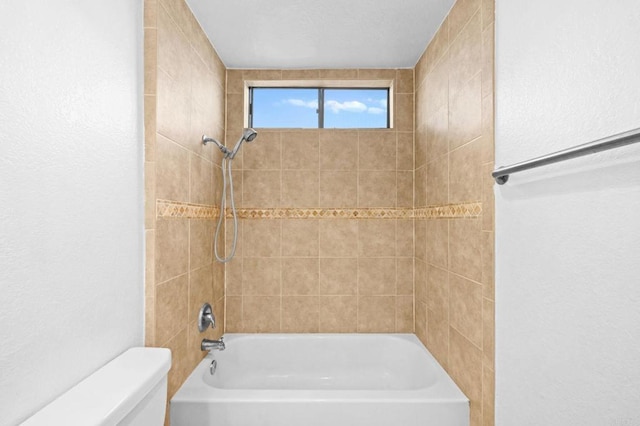 bathroom with toilet and tiled shower / bath combo