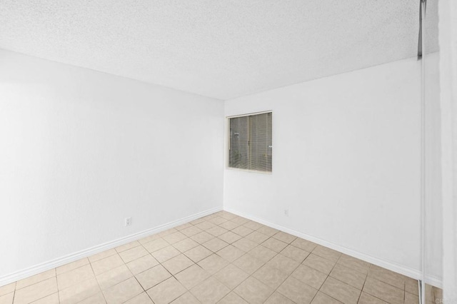 spare room with a textured ceiling and light tile patterned floors