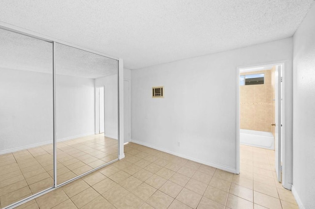 unfurnished bedroom with a textured ceiling, a closet, and light tile patterned flooring