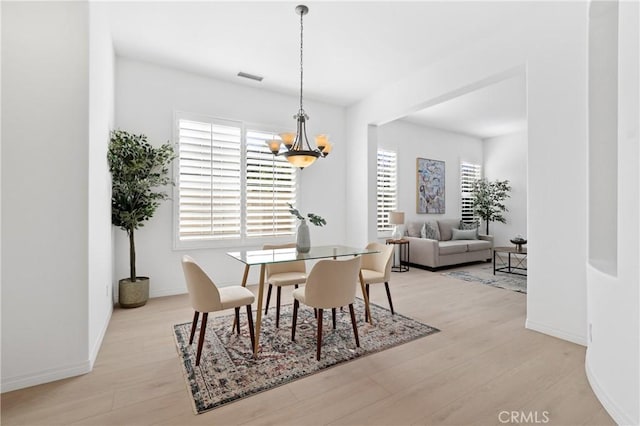 dining room with a notable chandelier, light wood-type flooring, and a wealth of natural light