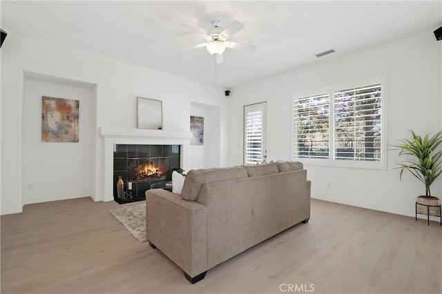 living room featuring a fireplace, ceiling fan, and light hardwood / wood-style floors