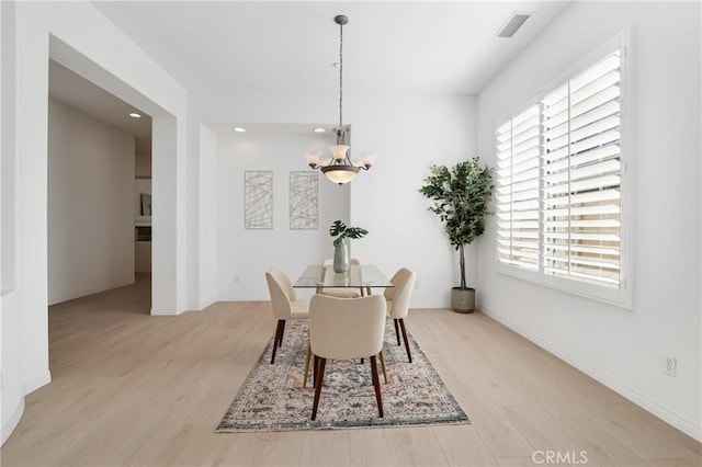 dining space with a notable chandelier and light hardwood / wood-style floors