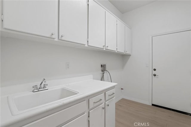 laundry room featuring sink, washer hookup, light hardwood / wood-style floors, and cabinets