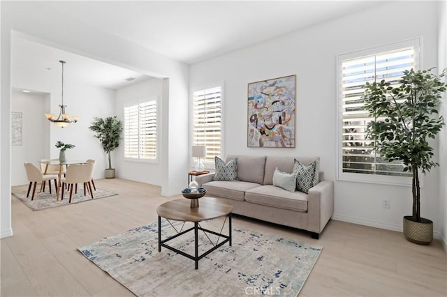 living room with light wood-type flooring, a chandelier, and plenty of natural light