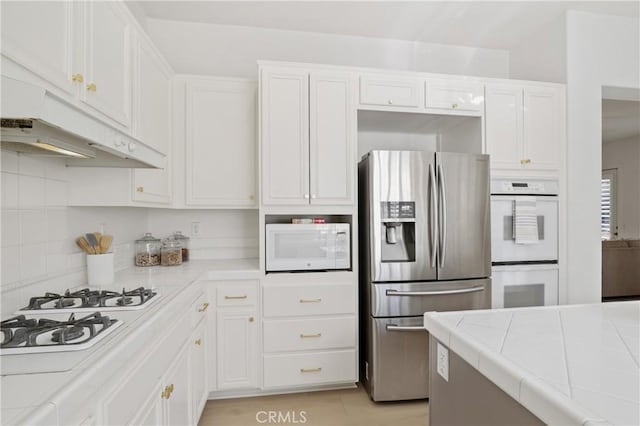 kitchen with white appliances, tile countertops, and white cabinets