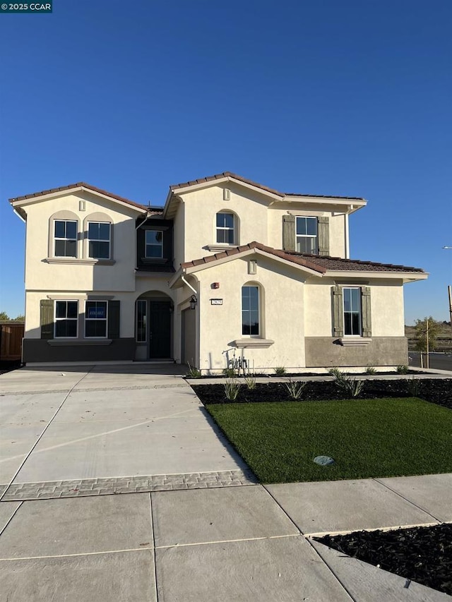 mediterranean / spanish house with a garage and a front lawn