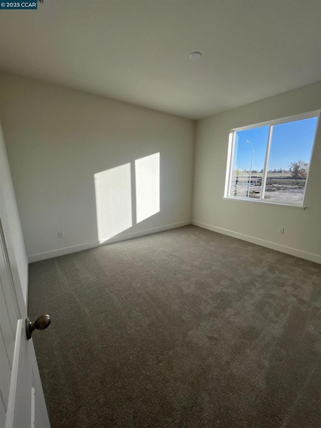 unfurnished room with dark carpet