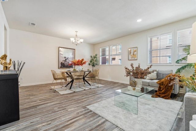 living room with an inviting chandelier, a wealth of natural light, and hardwood / wood-style flooring