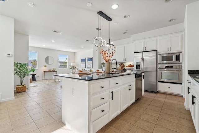 kitchen with stainless steel appliances, sink, light tile patterned floors, pendant lighting, and a kitchen island with sink