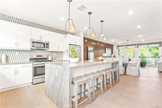 kitchen featuring a center island, hanging light fixtures, white cabinetry, appliances with stainless steel finishes, and ceiling fan