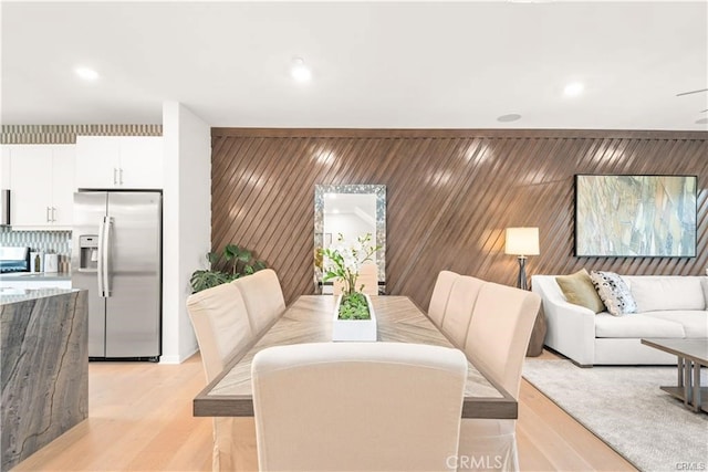 dining space with wooden walls and light hardwood / wood-style flooring