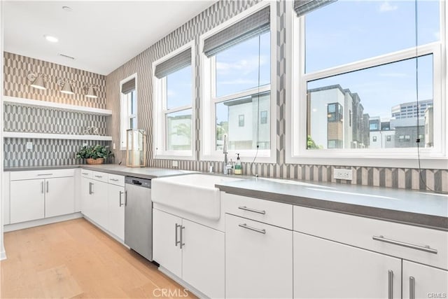 kitchen featuring sink, light wood-type flooring, dishwasher, and white cabinetry