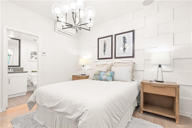 bedroom featuring a wall mounted AC, ensuite bathroom, and an inviting chandelier