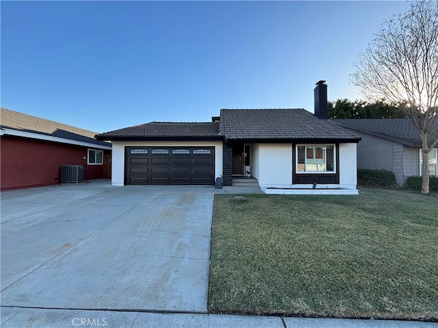 view of front of house with central AC unit, a garage, and a front lawn