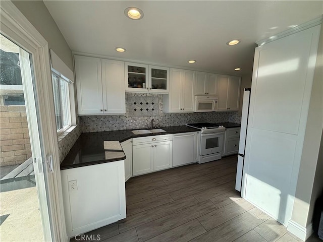 kitchen with white appliances, white cabinetry, backsplash, and sink