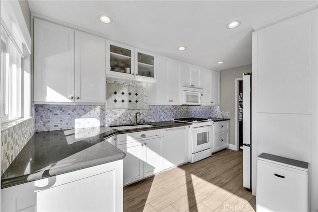 kitchen with sink, white cabinetry, white appliances, and kitchen peninsula