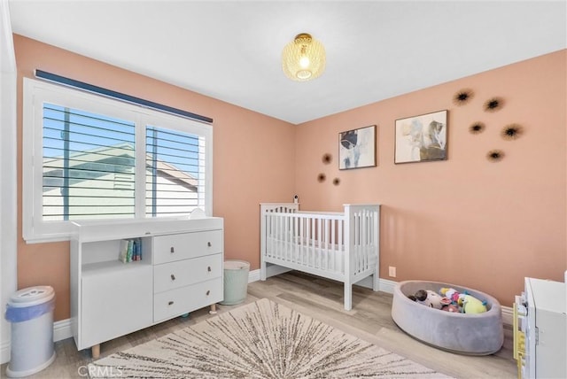 bedroom with light hardwood / wood-style floors and a nursery area