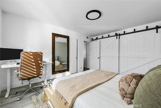 bedroom featuring hardwood / wood-style flooring and a barn door