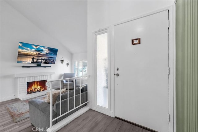 entrance foyer with hardwood / wood-style flooring, a brick fireplace, and lofted ceiling