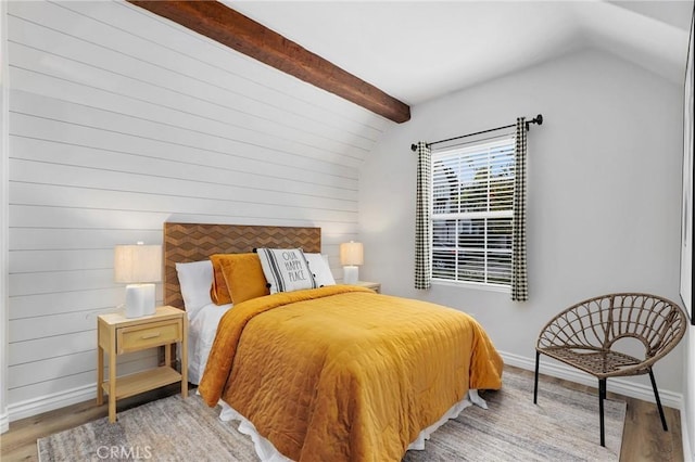 bedroom featuring light hardwood / wood-style floors, vaulted ceiling with beams, and wooden walls