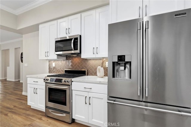 kitchen with tasteful backsplash, crown molding, white cabinetry, light hardwood / wood-style flooring, and appliances with stainless steel finishes