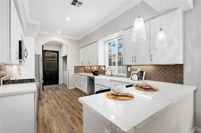 kitchen featuring stainless steel appliances, white cabinetry, tasteful backsplash, and decorative light fixtures