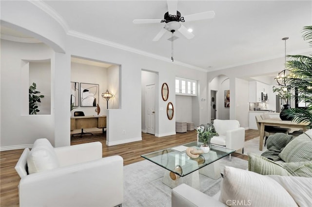 living room featuring light wood-type flooring, ceiling fan with notable chandelier, and ornamental molding