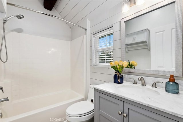 full bathroom featuring toilet, vanity, bathing tub / shower combination, and wood walls