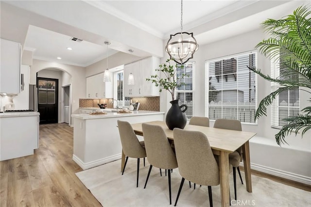 dining area featuring a notable chandelier, crown molding, and light hardwood / wood-style flooring