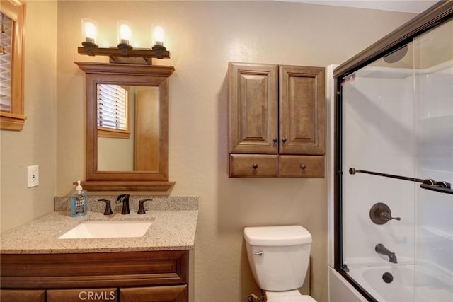 full bathroom featuring vanity, combined bath / shower with glass door, and toilet