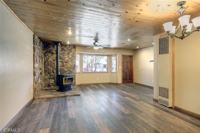 unfurnished living room featuring dark hardwood / wood-style flooring, wooden ceiling, a wood stove, and ceiling fan with notable chandelier