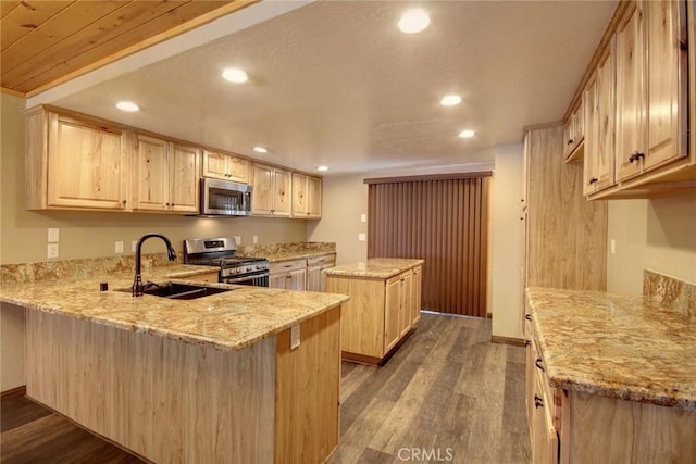 kitchen featuring appliances with stainless steel finishes, a center island, light stone countertops, and kitchen peninsula