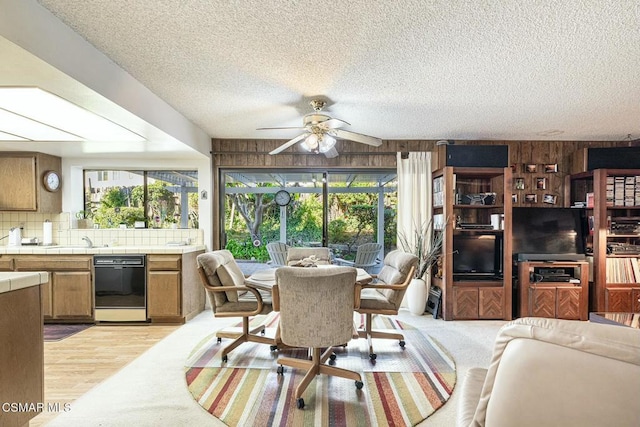 dining space with wooden walls, a textured ceiling, and ceiling fan